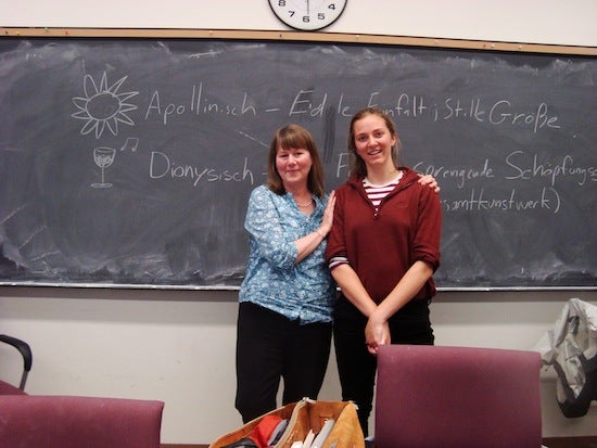 Student posing with professor in front of chalkboard